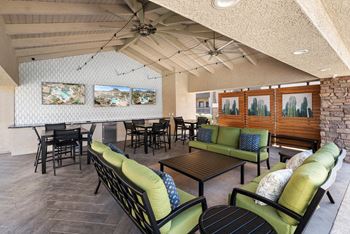 A room with a ceiling fan and a long couch with green pillows.